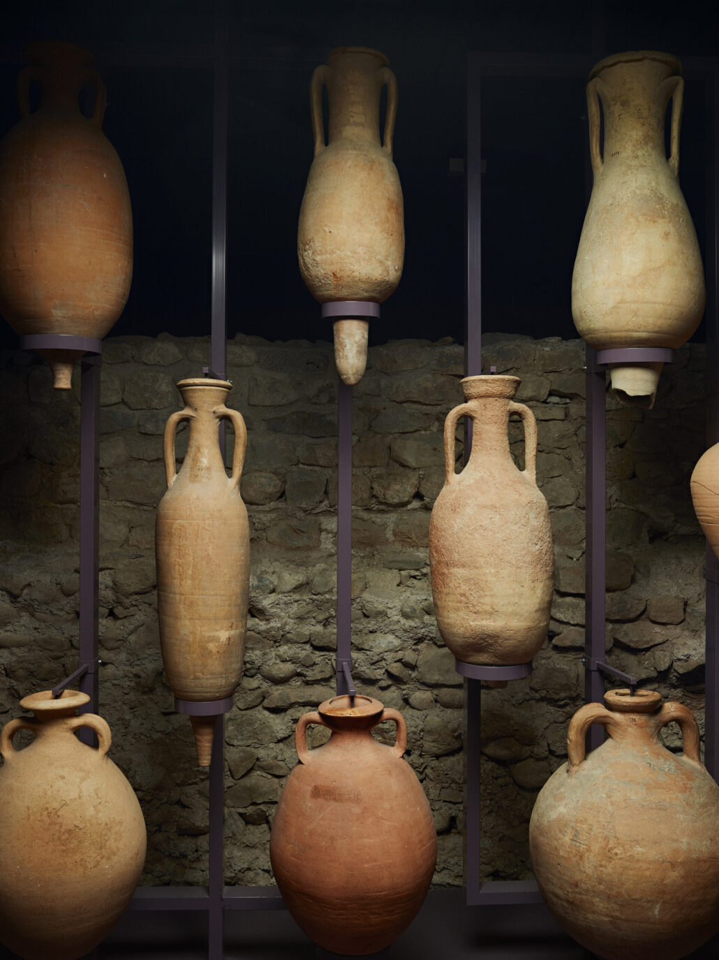 Plusieurs amphores romaines suspendues devant un mur